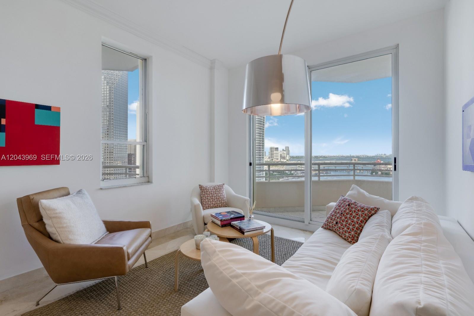 A bright living room features a white sofa, leather armchair, and a balcony with city views — 888 Brickell Key Dr # 2610, Miami FL 33131, MIAMI, FL