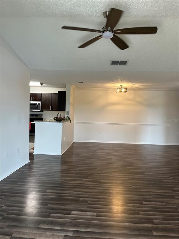 An open-concept living area features dark wood-look flooring, a ceiling fan, and an adjacent kitchen — 1939 SUMMER CLUB APT DRIVE UNIT 315, OVIEDO, FL