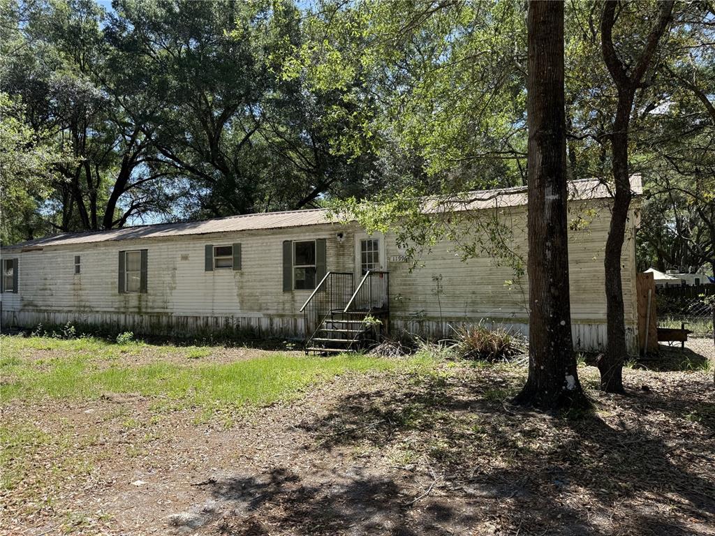 A weathered, single-wide mobile home sits on a wooded lot with metal stairs — 11992/11996 SW 146TH PLACE, DUNNELLON, FL