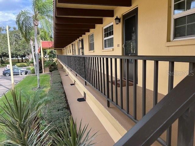 An exterior view of an apartment building walkway with a metal railing and palm trees — 1845 S HIGHLAND AVENUE UNIT 4-9, CLEARWATER, FL