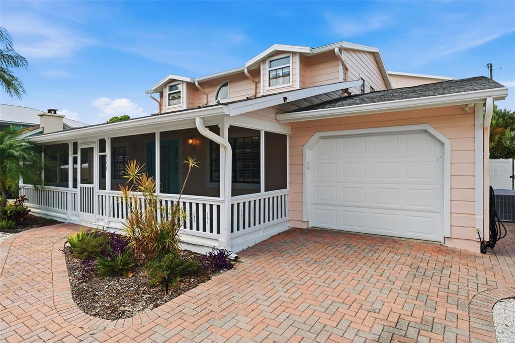 A two-story house with peach siding, a white garage, and a screened-in front porch — 345 BAILEY STREET, SAFETY HARBOR, FL