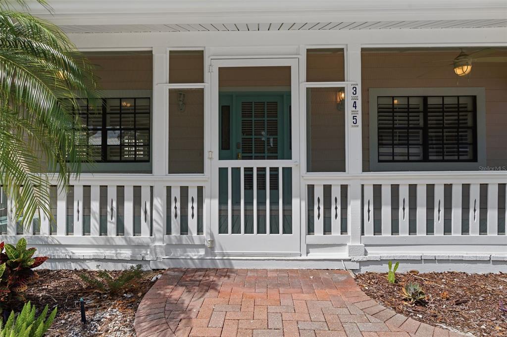 A front porch with a white screen door, railing, and a brick walkway — 345 BAILEY STREET, SAFETY HARBOR, FL