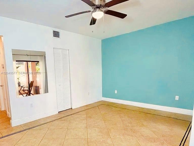 An empty room features a ceiling fan, a blue accent wall, and tiled flooring — 585 NE 66th St # 3, Miami FL 33138, MIAMI, FL