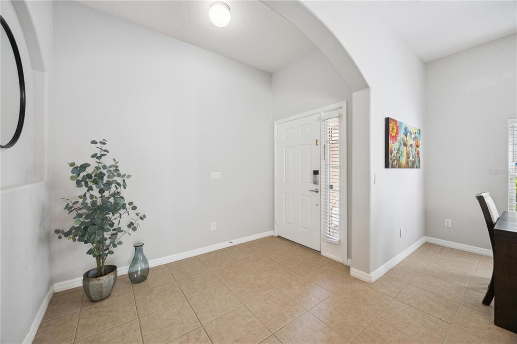 An entryway with light-colored walls, tile flooring, a white front door, and a potted plant — 11625 GREAT COMMISSION WAY, ORLANDO, FL