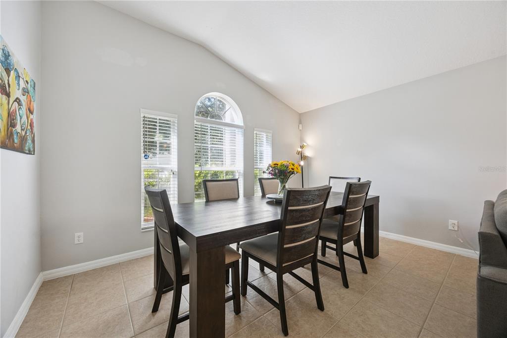 A dining room features a dark wood table, six chairs, and three windows with blinds — 11625 GREAT COMMISSION WAY, ORLANDO, FL