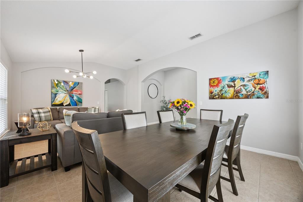 A dining room with a dark wood table and chairs adjacent to a living area — 11625 GREAT COMMISSION WAY, ORLANDO, FL