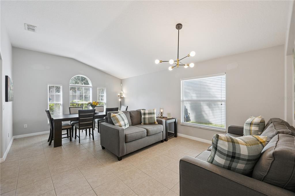 A living and dining area with gray sofas, a dark wood table, and tile flooring — 11625 GREAT COMMISSION WAY, ORLANDO, FL