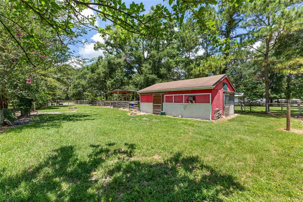 A red barn with a white base sits in a grassy field surrounded by trees — 16353 NW 130 STREET, WILLISTON, FL