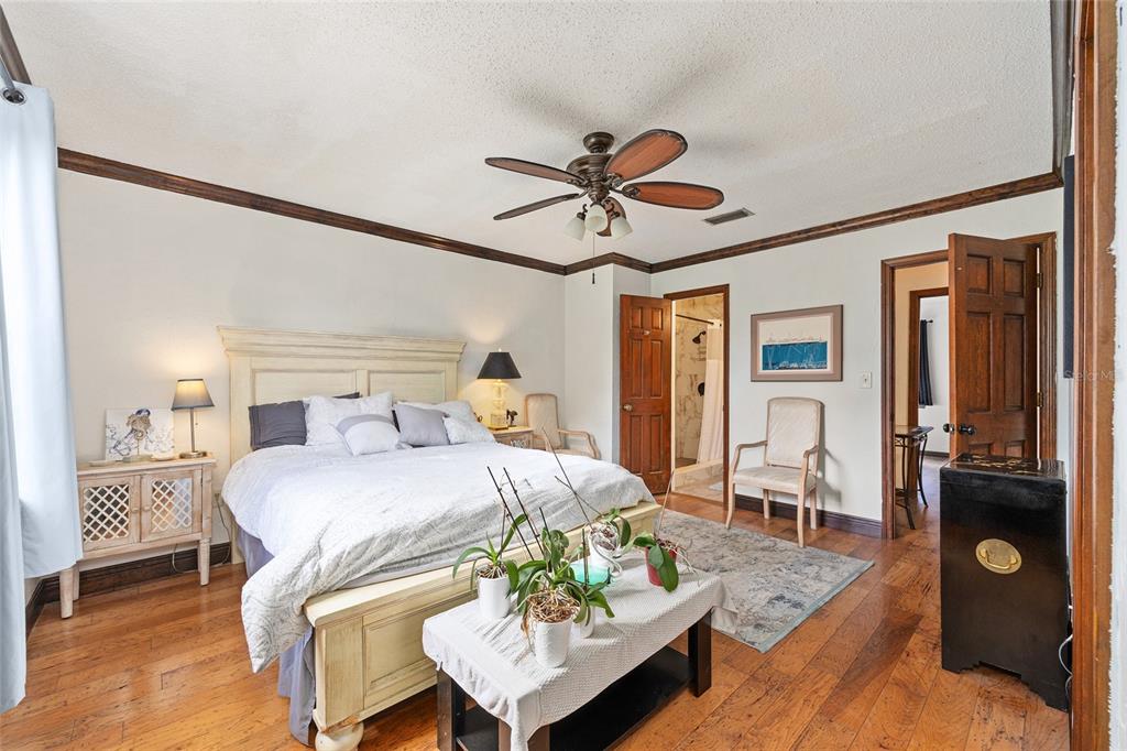 A bedroom features a wooden bed, hardwood floors, a ceiling fan, and two doorways — 16353 NW 130 STREET, WILLISTON, FL