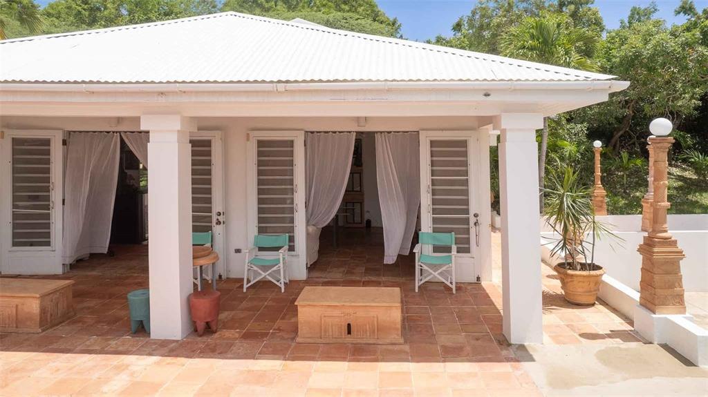 A covered patio with terracotta tile flooring, white columns, and folding chairs overlooks a garden — 20 CALLE RAMOS RIVERA, VIEQUES, PR