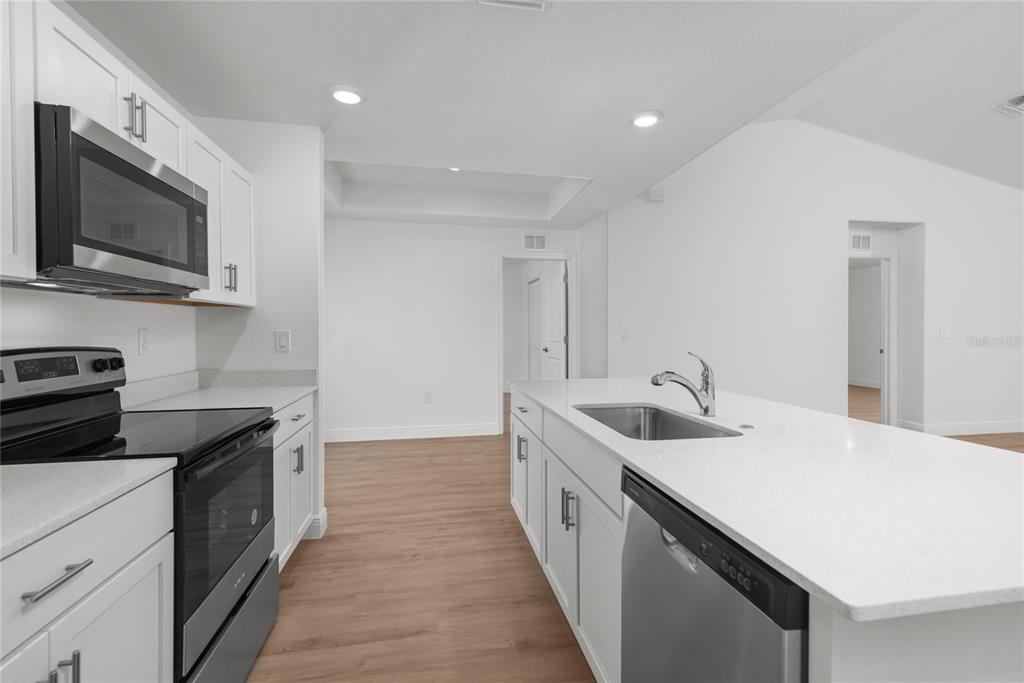 A modern kitchen features white cabinets, stainless steel appliances, and a large quartz-topped island — 4668 ADDLEY AVENUE, NORTH PORT, FL