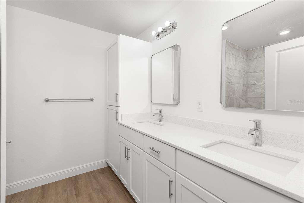 A modern bathroom features a double vanity with white cabinets, quartz countertops, and two mirrors — 4668 ADDLEY AVENUE, NORTH PORT, FL
