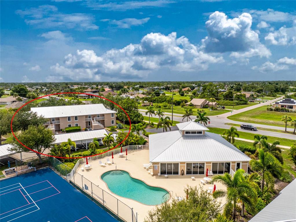 An aerial view shows a two-story apartment building, a swimming pool, and a tennis court — 9500 FIDDLERS GREEN CIRCLE UNIT 101, ROTONDA WEST, FL
