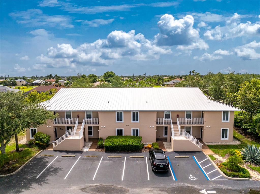 An aerial view of a two-story apartment building with a white metal roof — 9500 FIDDLERS GREEN CIRCLE UNIT 101, ROTONDA WEST, FL