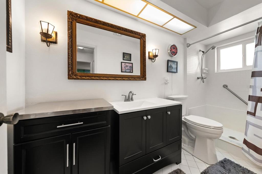 A bathroom features a black vanity, a large ornate mirror, and a shower-tub combination — 1651 S LAKE AVENUE UNIT 3, CLEARWATER, FL