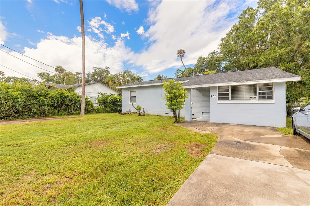 A light blue single-story house with a concrete driveway and a grassy front yard — 730 FLANDERS AVENUE, DAYTONA BEACH, FL