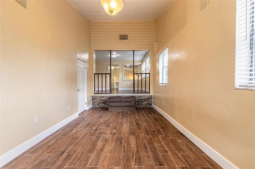A room with wood-look tile flooring leads up stone steps to a raised, railed area — 730 FLANDERS AVENUE, DAYTONA BEACH, FL