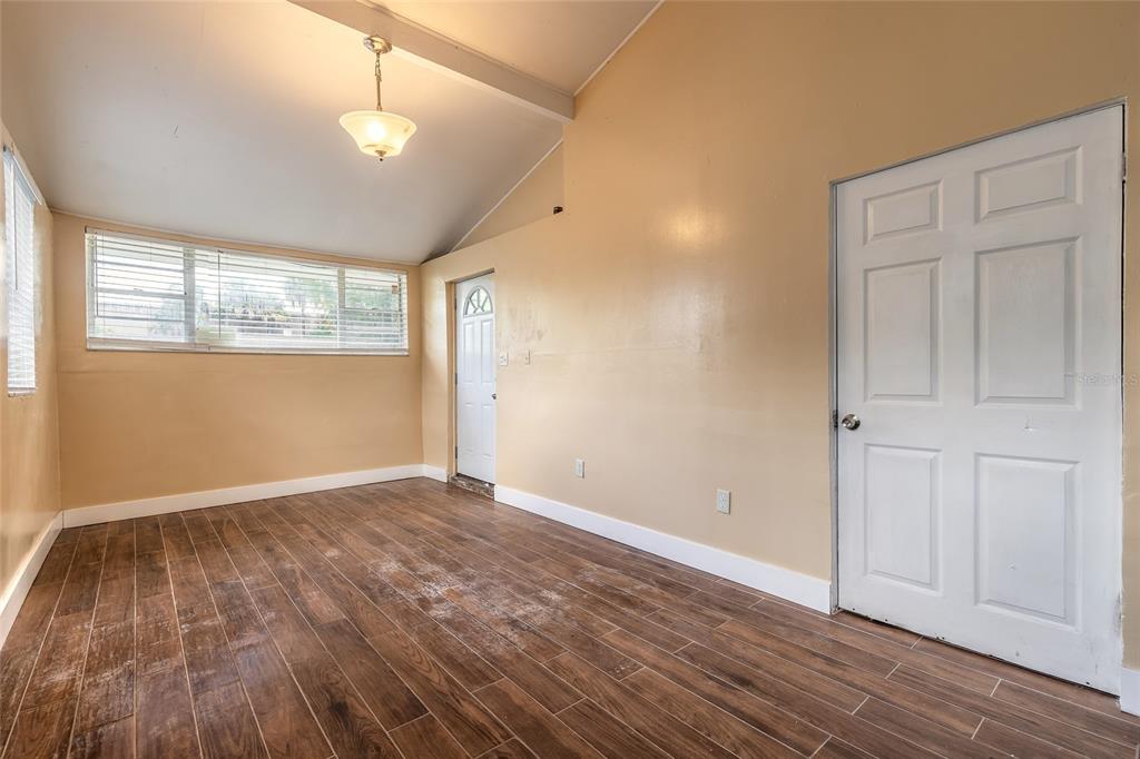 An empty room with tan walls, wood-look tile flooring, and two white doors — 730 FLANDERS AVENUE, DAYTONA BEACH, FL
