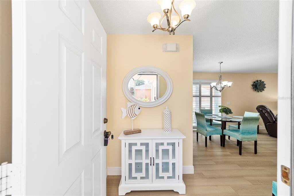 An entryway features a white cabinet, an oval mirror, and a view into the dining area — 911 MEDIRA DRIVE, LADY LAKE, FL