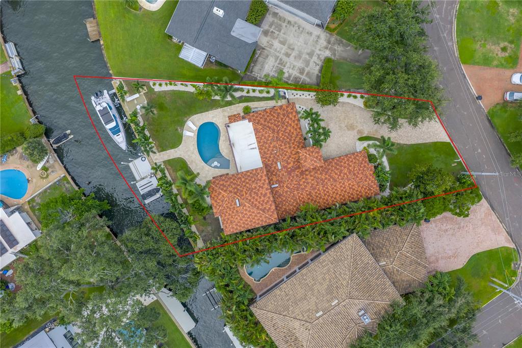 Aerial view of a waterfront house with a tiled roof, swimming pool, and boat dock — 145 BAY POINT DRIVE NE, ST PETERSBURG, FL