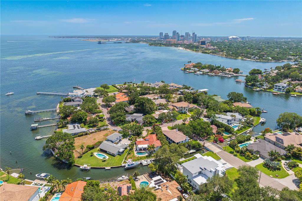 An aerial view of a waterfront residential neighborhood with a city skyline in the distance — 145 BAY POINT DRIVE NE, ST PETERSBURG, FL