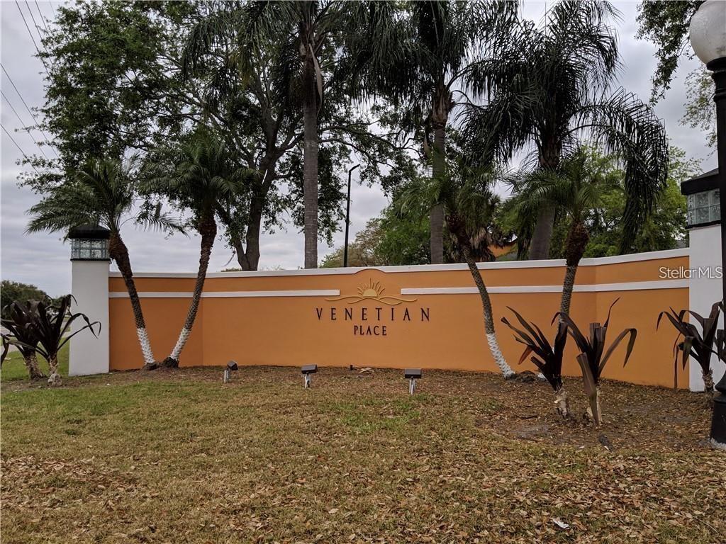 A tan stucco entrance wall with the text Venetian Place stands before several palm trees — 4572 COMMANDER DRIVE UNIT 1213, ORLANDO, FL
