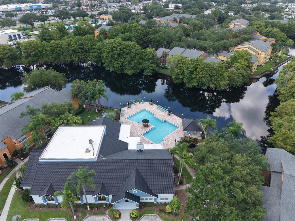 An aerial view shows a community clubhouse with a pool overlooking a lake — 4572 COMMANDER DRIVE UNIT 1213, ORLANDO, FL