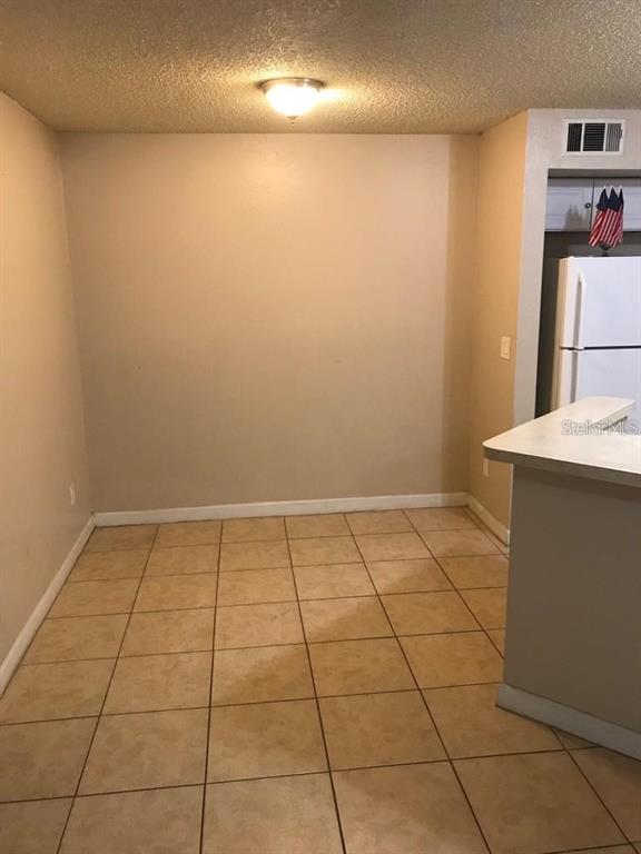 A dining area features tan walls, a textured ceiling, and light-colored square floor tiles — 4572 COMMANDER DRIVE UNIT 1213, ORLANDO, FL