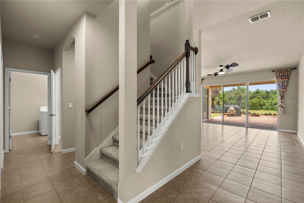 An interior view shows a tiled foyer with a carpeted staircase and a living area — 2355 SABASTIAN STREET, MOUNT DORA, FL