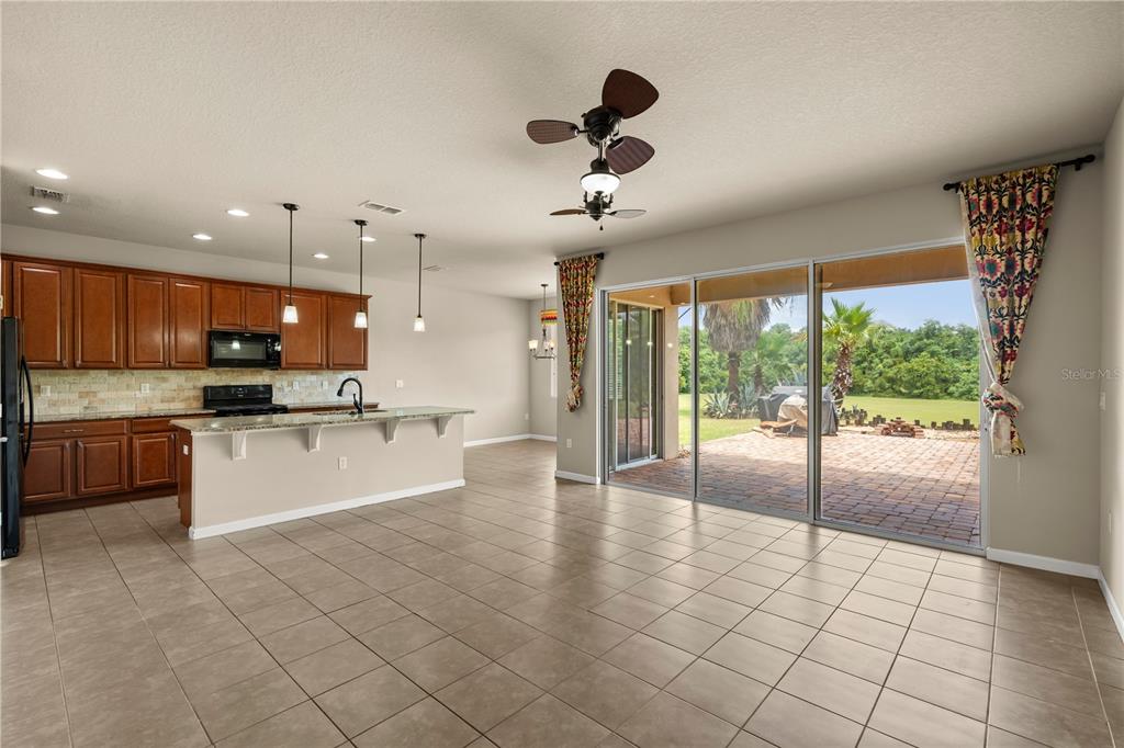 An open-concept kitchen and living area features tile flooring, wood cabinetry, and sliding glass doors — 2355 SABASTIAN STREET, MOUNT DORA, FL