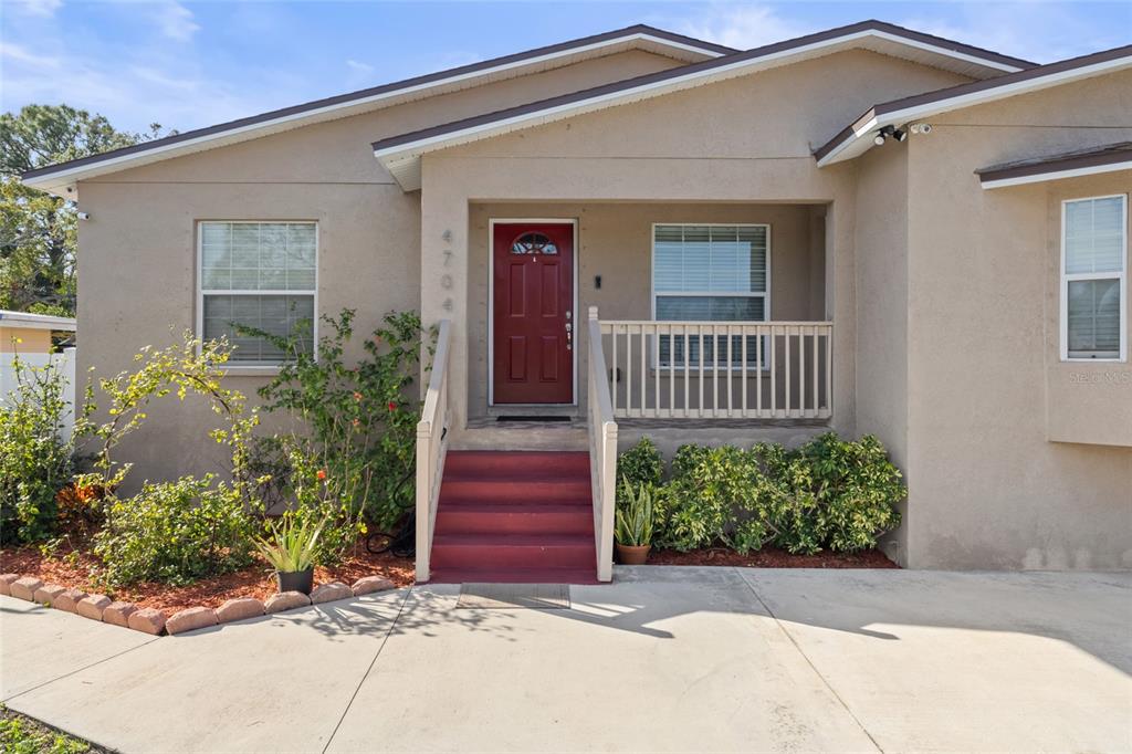A tan house exterior features a red front door, red steps, and a small porch — 4704 TOWN N COUNTRY BOULEVARD, TAMPA, FL
