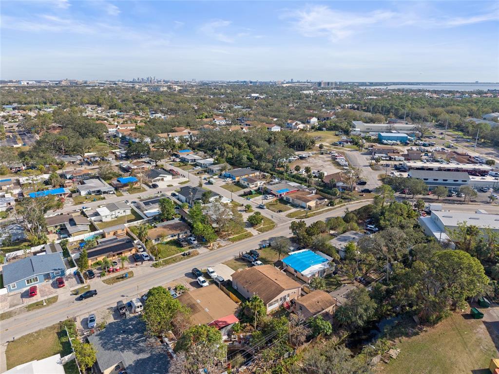 An aerial view shows a residential neighborhood with houses, streets, and a distant city skyline — 4704 TOWN N COUNTRY BOULEVARD, TAMPA, FL