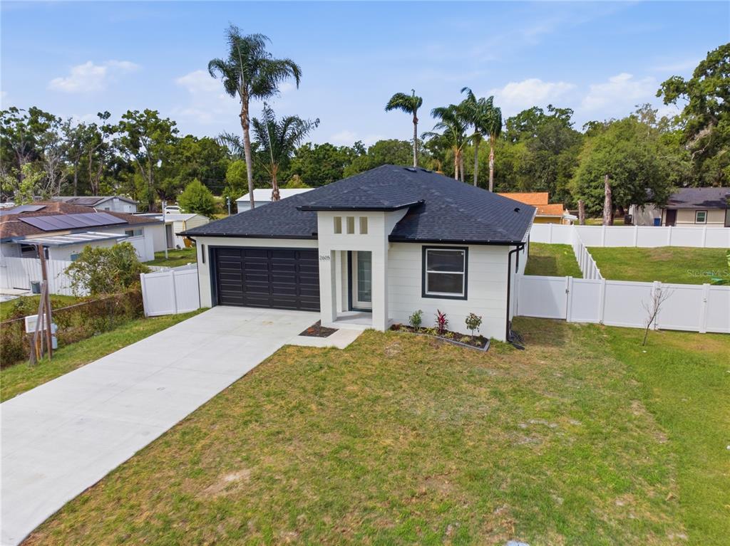 An exterior view of a single-story house with a black roof, white siding, and garage — 2605 S 70TH STREET, TAMPA, FL