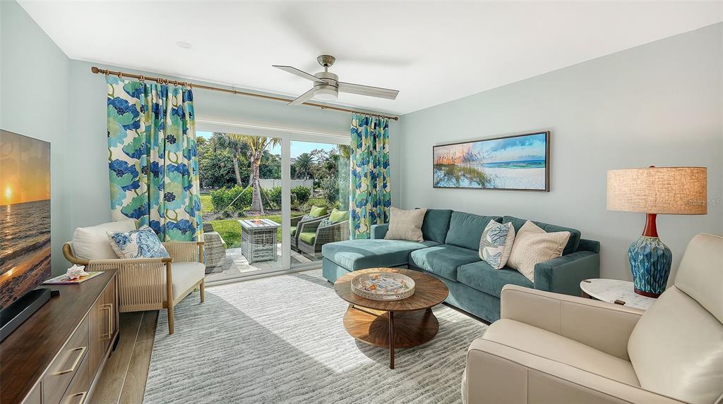 A living room features a teal sectional sofa, a round coffee table, and sliding glass doors — 4720 GULF OF MEXICO DRIVE UNIT Villa 2, LONGBOAT KEY, FL