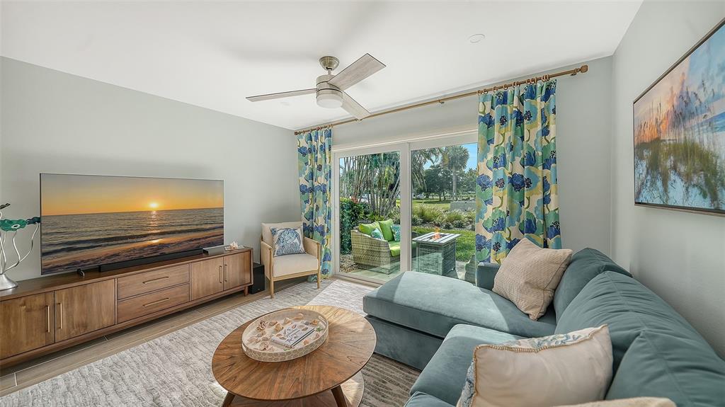 A living room features a blue sectional sofa, a wooden media console, and sliding doors — 4720 GULF OF MEXICO DRIVE UNIT Villa 2, LONGBOAT KEY, FL