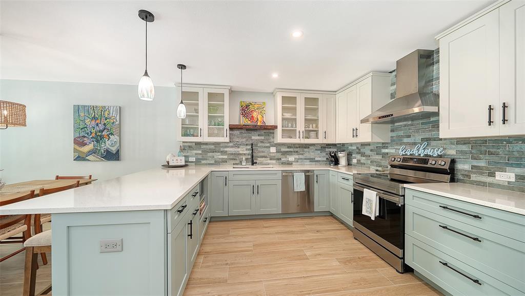 A kitchen features light blue cabinets, white countertops, a tiled backsplash, and stainless steel appliances — 4720 GULF OF MEXICO DRIVE UNIT Villa 2, LONGBOAT KEY, FL