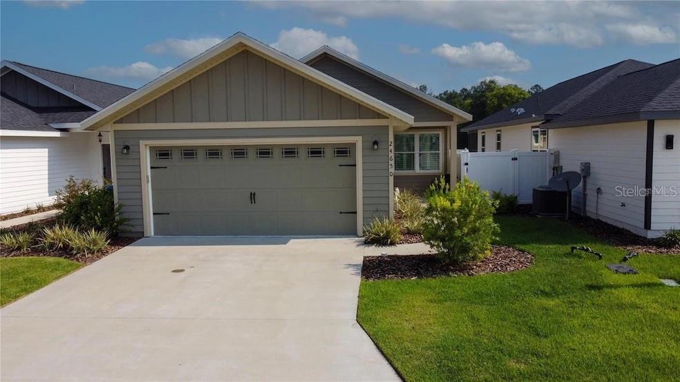 A single-story house with a two-car garage, gray siding, and a concrete driveway — 24650 SW 17TH PLACE, NEWBERRY, FL