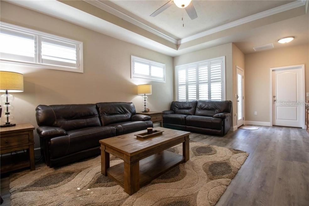 A living room features two dark leather sofas, a wooden coffee table, and wood-look flooring — 24650 SW 17TH PLACE, NEWBERRY, FL