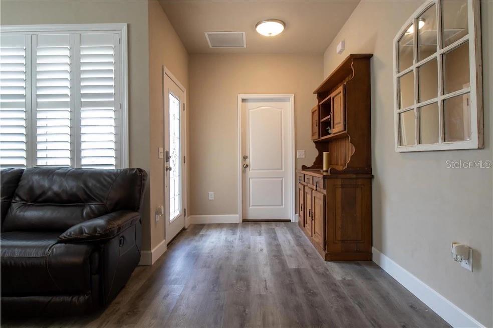 A room with wood-look flooring, a dark leather sofa, a wooden hutch, and a door — 24650 SW 17TH PLACE, NEWBERRY, FL