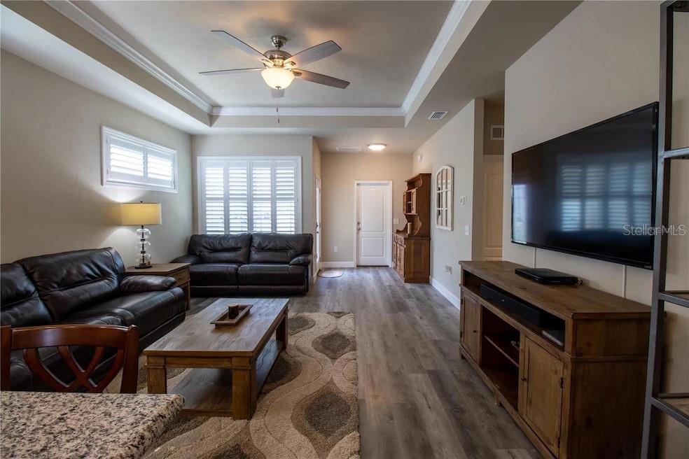 A living room features dark leather sofas, a wooden coffee table, and a wall-mounted television — 24650 SW 17TH PLACE, NEWBERRY, FL