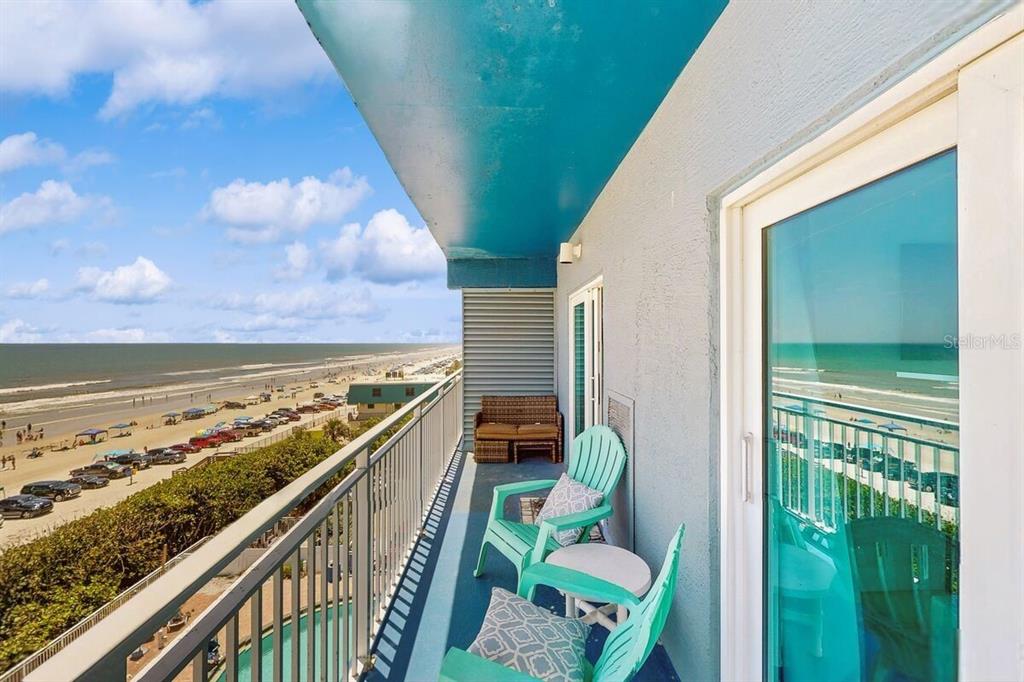 A balcony with turquoise chairs overlooks a sandy beach and the ocean — 611 S ATLANTIC AVENUE UNIT 4512, NEW SMYRNA BEACH, FL