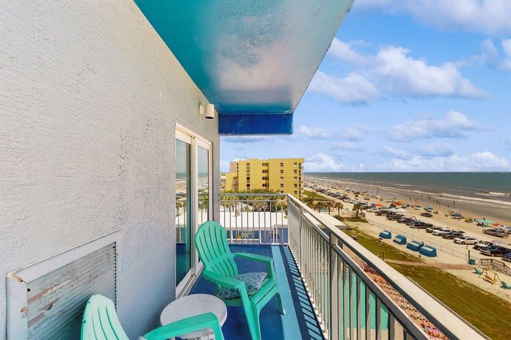 A balcony with two teal chairs overlooks a sandy beach and the ocean — 611 S ATLANTIC AVENUE UNIT 4512, NEW SMYRNA BEACH, FL
