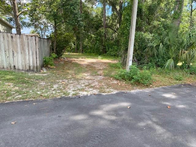 A dirt driveway leads into a wooded lot next to a wooden fence — 00, DELAND, FL