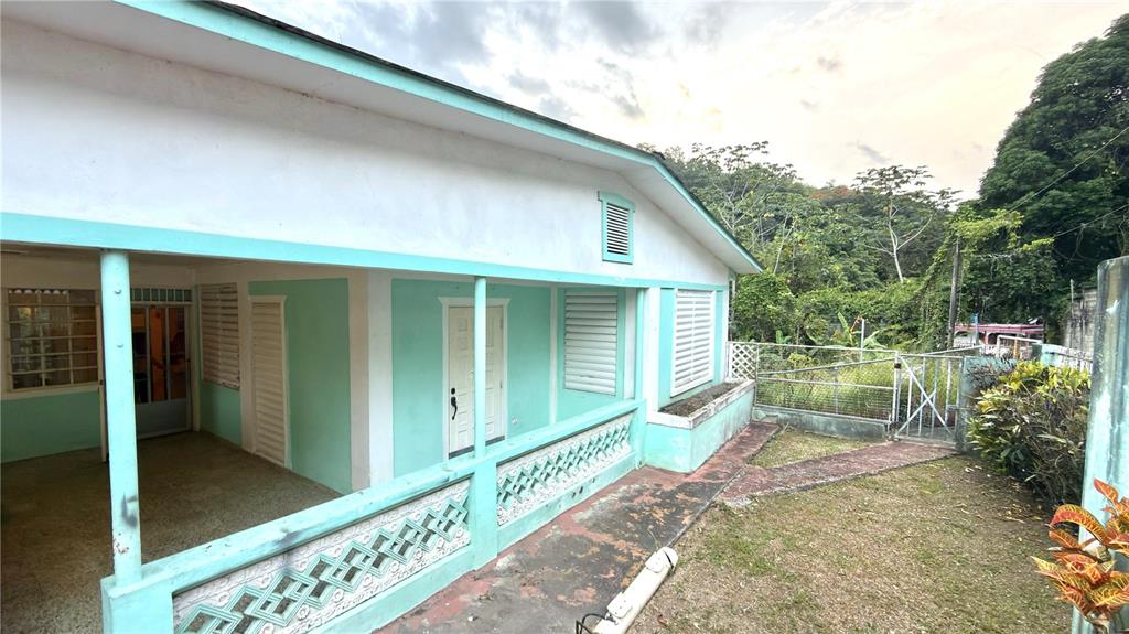 A light green house features a covered porch with decorative concrete railings and white trim — . 123 KM 16.1 INT., PONCE, PR