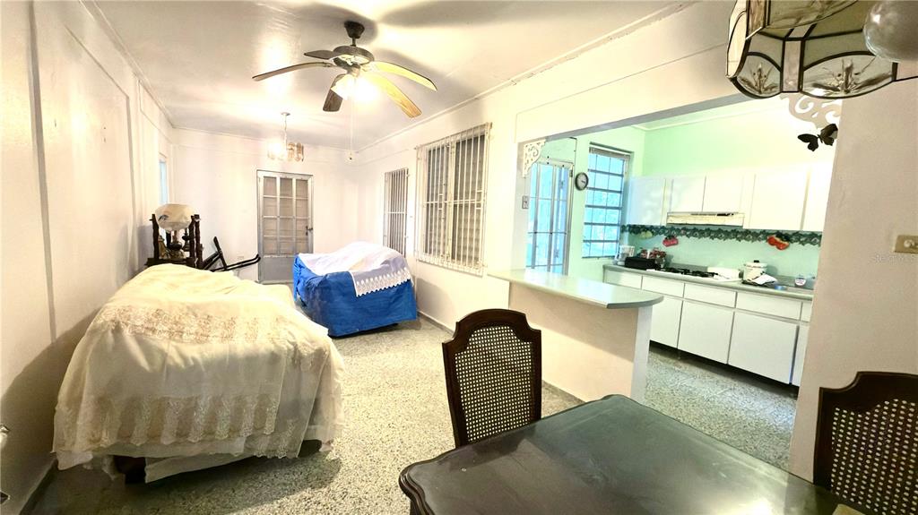 A dining area with a ceiling fan leads into a kitchen with white cabinets — . 123 KM 16.1 INT., PONCE, PR