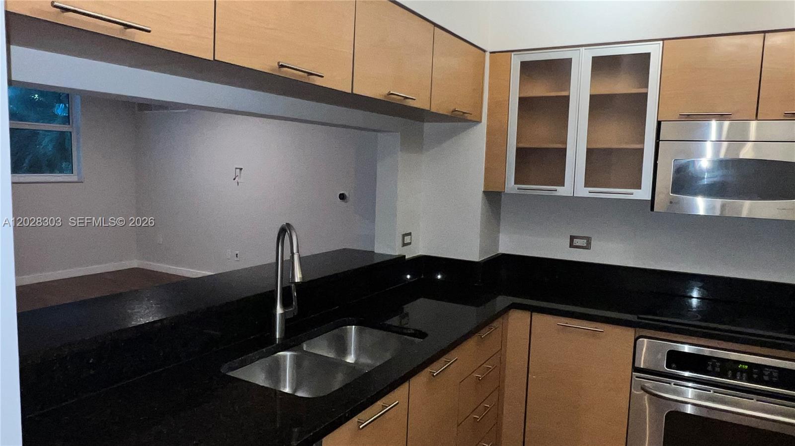 A kitchen features light wood cabinets, black countertops, and stainless steel appliances — 31 SE 5th St # 411, Miami FL 33131, MIAMI, FL