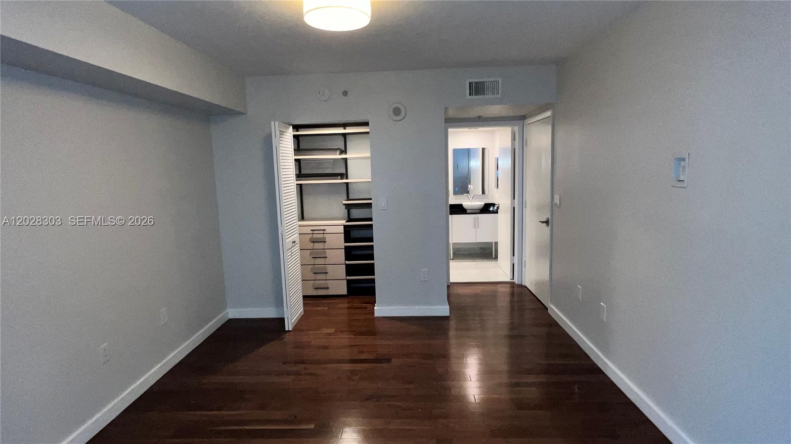 A bedroom features dark hardwood floors, a built-in closet system, and an adjacent bathroom — 31 SE 5th St # 411, Miami FL 33131, MIAMI, FL