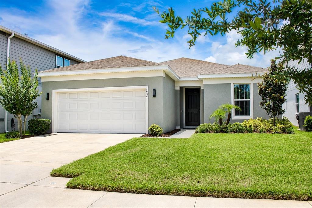 A single-story house with a gray stucco exterior, a two-car garage, and a front lawn — 1634 GROVELINE RD, ST CLOUD, FL