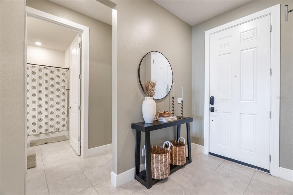A foyer features a black console table, a round mirror, and a doorway to a bathroom — 1634 GROVELINE RD, ST CLOUD, FL