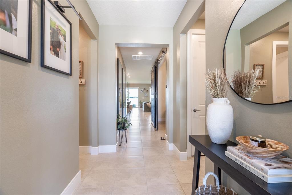 A bright hallway features tile flooring, a console table with decor, and a round mirror — 1634 GROVELINE RD, ST CLOUD, FL